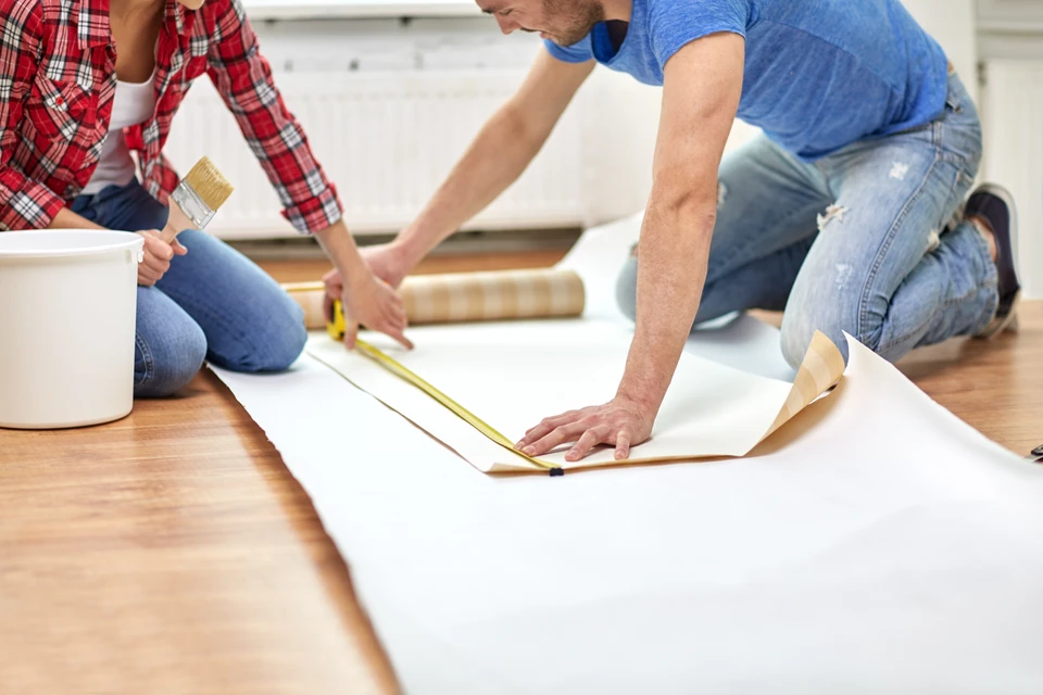 concept de réparation, de construction et de personnes - gros plan sur un couple avec une règle qui mesure le papier peint à la maison