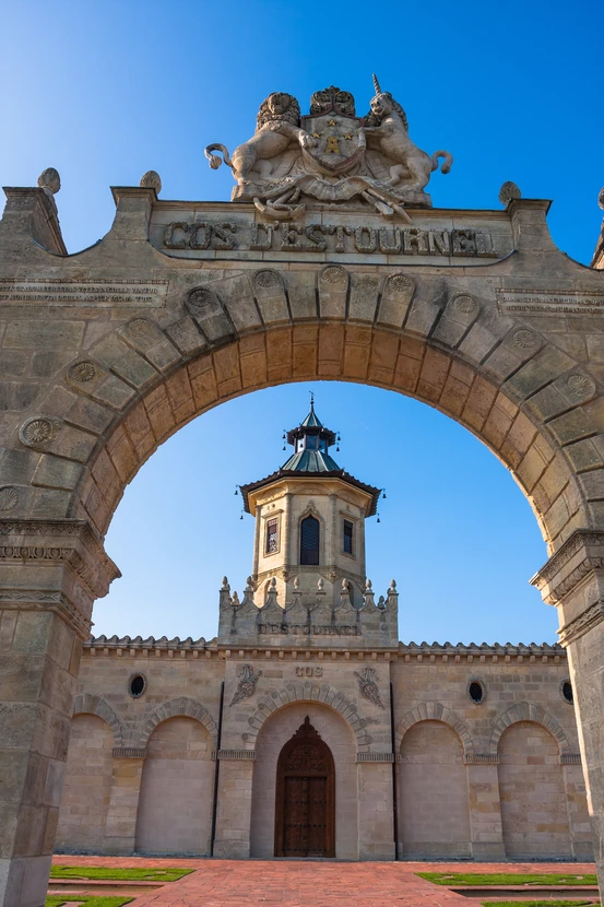 Extérieur d'édifice religieux avec arche en pierre sculptée au premier plan encadrant une église au second plan