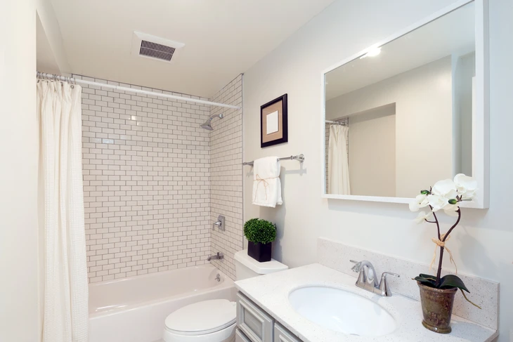 Salle de bain moderne avec baignoire encastrée, carrelage métro blanc aux joints gris, rideau de douche beige