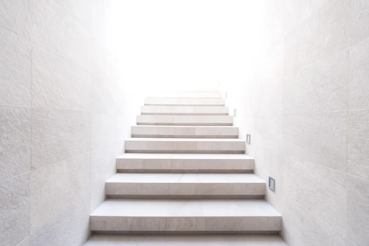 Escalier moderne en béton ciré beige dans un environnement minimaliste aux murs blancs texturés