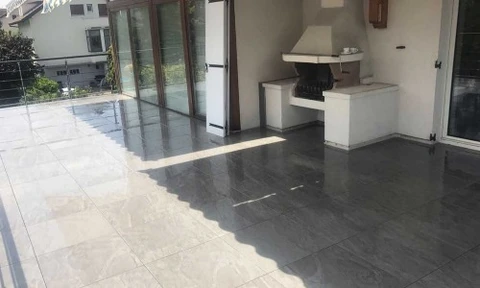Salon moderne minimaliste avec sol en béton ciré gris, murs en béton apparent, cheminée encastrée double-face à foyer ouvert