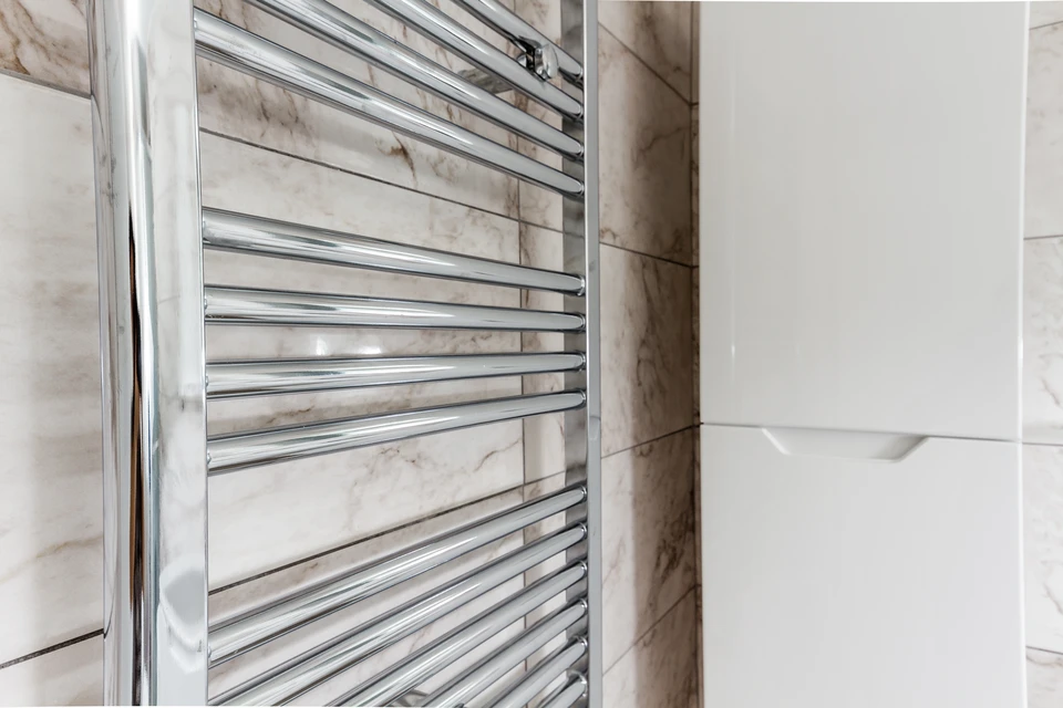 Salle de bain moderne avec radiateur sèche-serviettes chromé fixé au mur