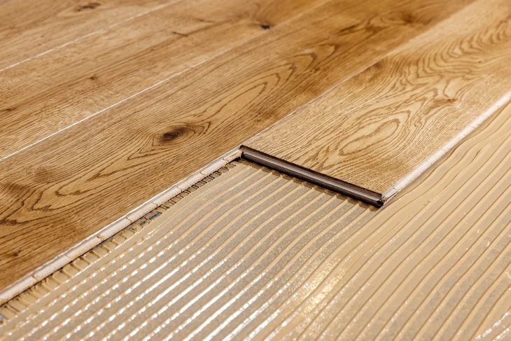 Chantier de pose de parquet en bois massif sur plancher chauffant électrique