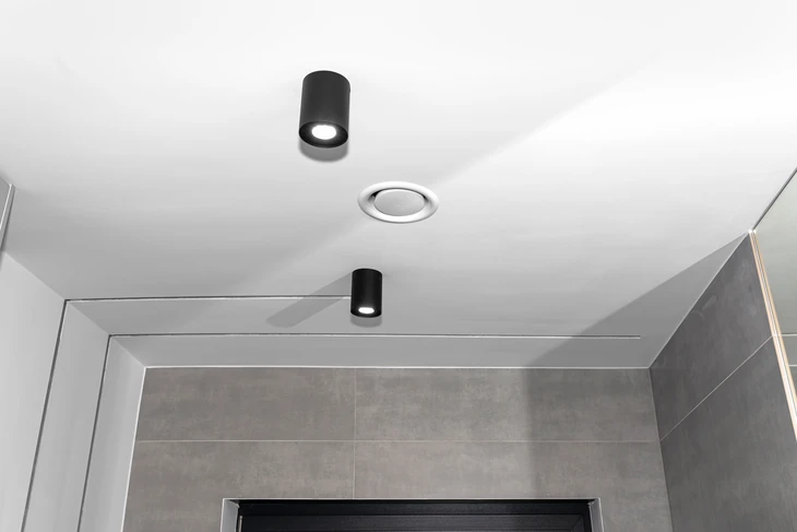 Intérieur moderne avec plafond blanc équipé de luminaires encastrés et apparents