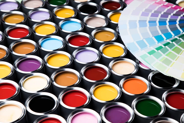 Scène d'atelier de peinture avec multiples pots de peinture ouverts disposés sur surface noire, nuancier colorimétrique professionnel déployé