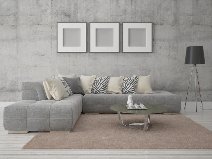 Salon moderne avec canapé d'angle gris en tissu chiné, coussins décoratifs beiges et zébrés