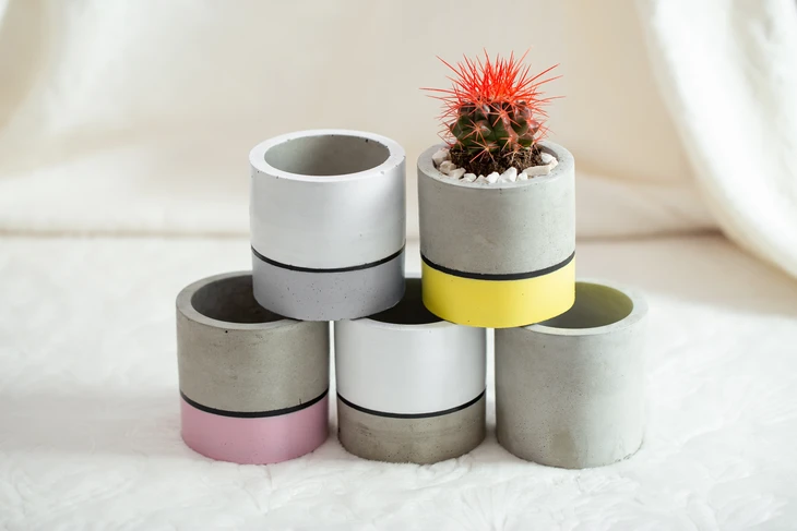 Scène d'intérieur sur surface blanche avec collection de pots cylindriques en béton empilés en pyramide