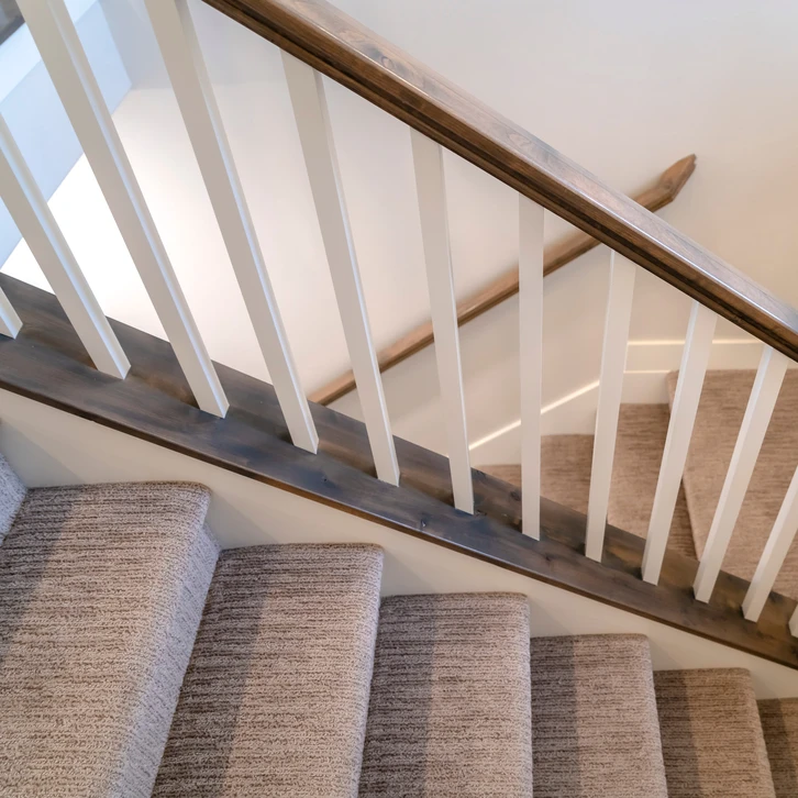 Escalier intérieur résidentiel avec marches recouvertes de moquette rayée beige et grise