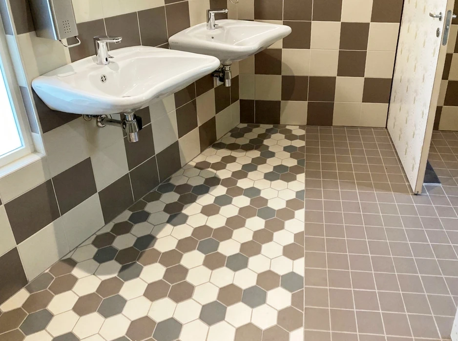 Salle de bains commerciale avec deux lavabos suspendus blancs, robinetterie chromée