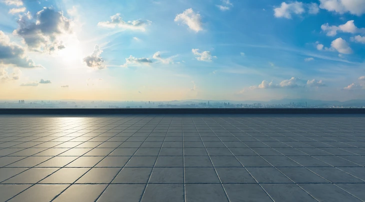 Espace extérieur ouvert avec sol carrelé en dalles géométriques grises sous ciel nuageux