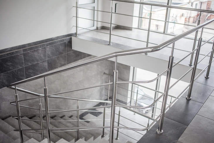 Escalier moderne en béton avec rampe et garde-corps en acier inoxydable dans un bâtiment commercial ou résidentiel contemporain