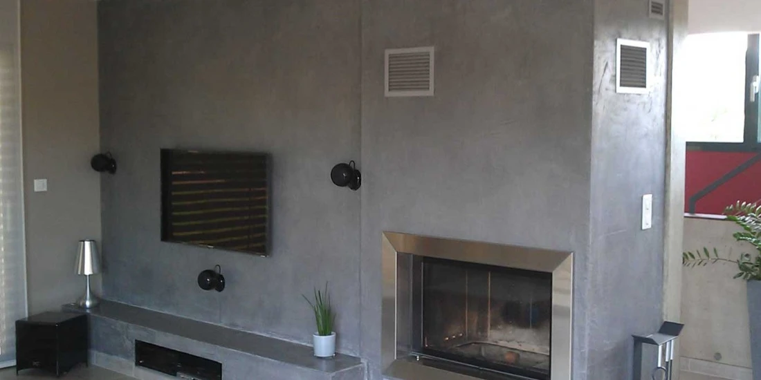 Intérieur contemporain lumineux avec poêle à bois encastré dans un pilier en pierre sculptée texturée gris anthracite