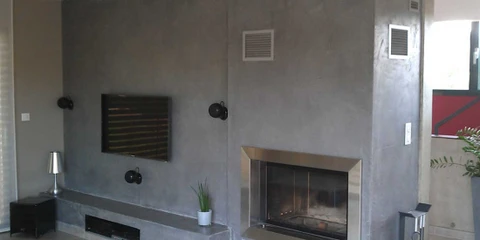 Salon moderne minimaliste avec sol en béton ciré gris, murs en béton apparent, cheminée encastrée double-face à foyer ouvert