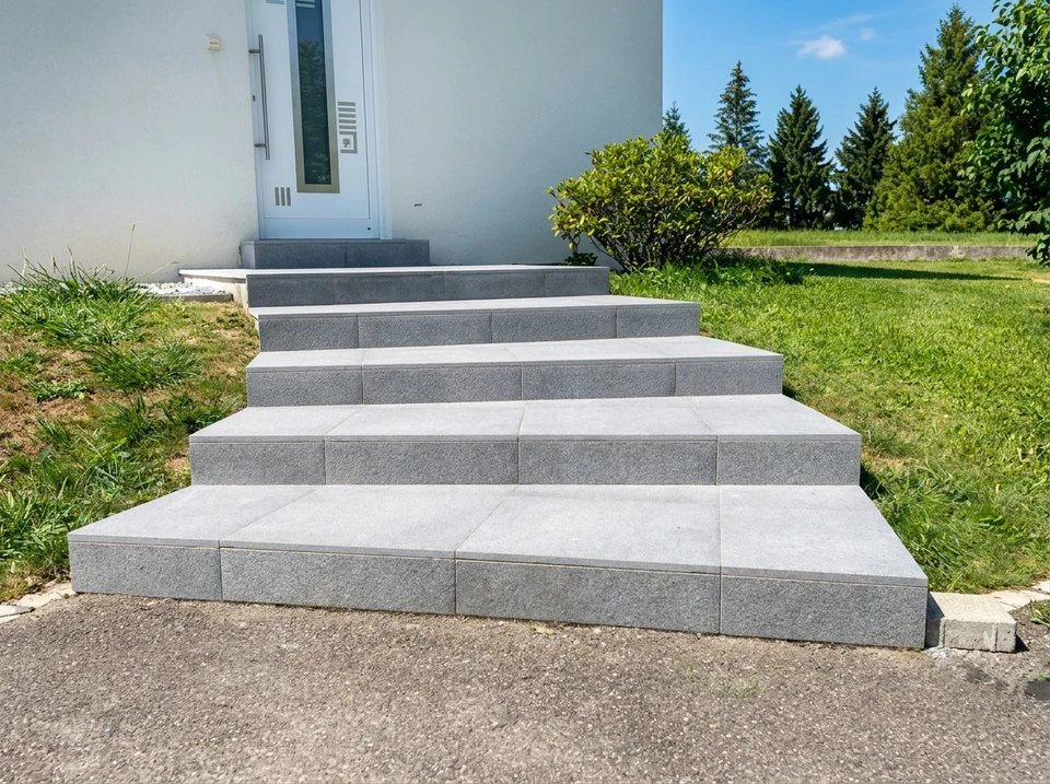 Photographie réaliste d'une terrasse extérieure résidentielle luxueuse avec un carrelage de qualité récemment posé, invitant à la détente. La terrasse est agréablement aménagée avec du mobilier d'extérieur confortable (chaises longues, table basse), des plantes en pots, et une ambiance lumineuse de jour ensoleillé. Le carrelage doit être clairement visible et bien mis en œuvre, montrant différentes textures ou finitions de revêtement de sol extérieur. L'espace donne envie de passer du temps dehors et valorise l'esthétique et la qualité de la pose.