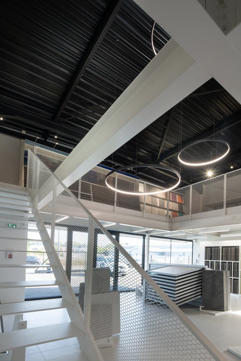 Showroom automobile intérieur avec rangées de véhicules neufs alignés sur sol carrelé blanc brillant