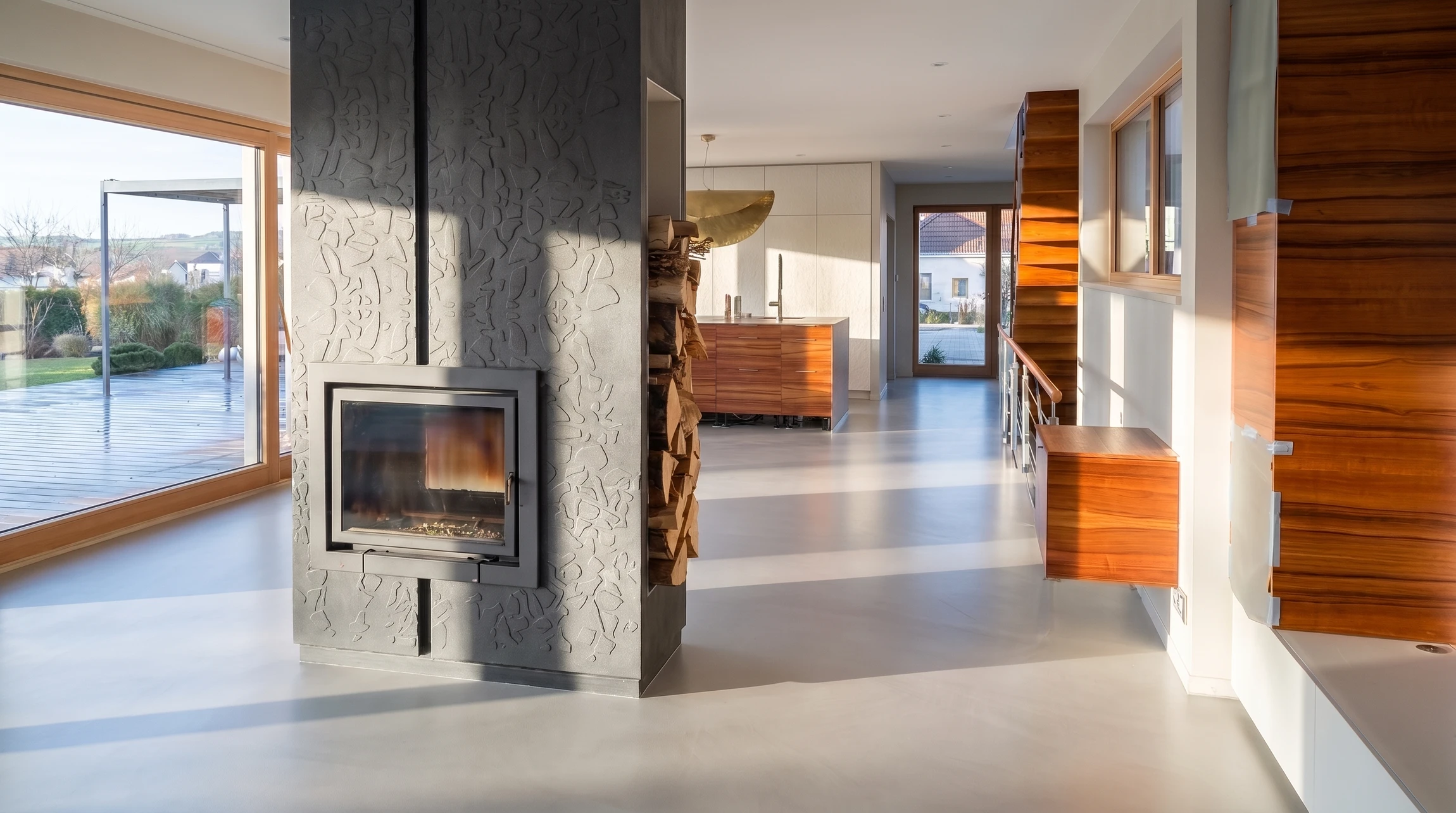 Salon moderne minimaliste avec sol en béton ciré gris, murs en béton apparent, cheminée encastrée double-face à foyer ouvert